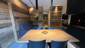 A modern kitchen with wooden walls, a dining table, and blue chairs. - Rental of 12 gîtes and 1 chalet that can accommodate 2 to 10 people. (ROCHESSON)
