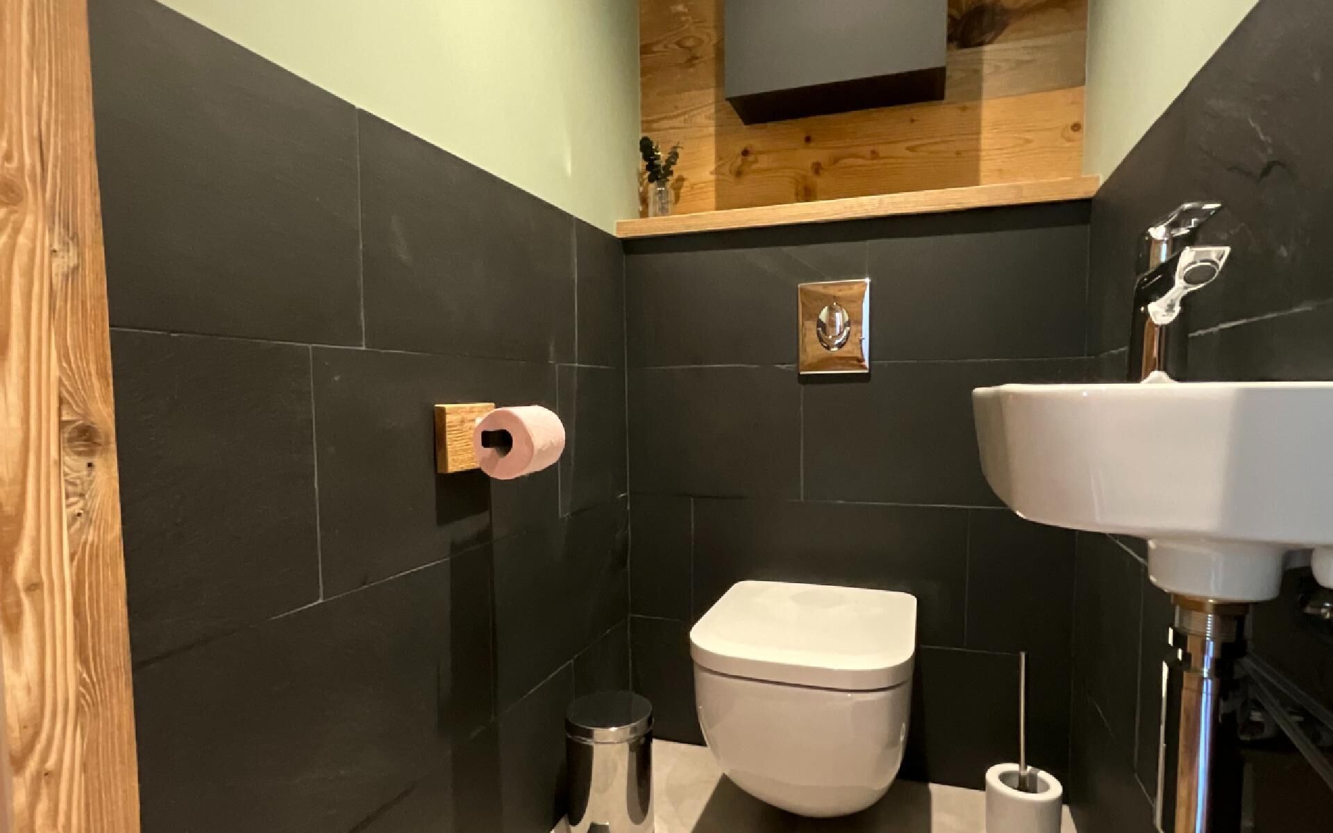 Een moderne badkamer met toilet, wastafel en toiletrolhouder.