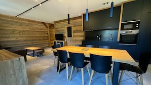 Una cocina moderna con armarios oscuros, una mesa de comedor de madera y sillas azules.