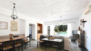 A spacious living area with a wooden dining table, a sofa, and a fireplace. - Villa Breath of the Sea (Hersonissos)