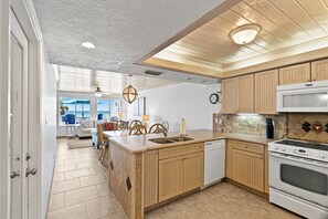 Una cocina con muebles de madera, un lavamanos, una estufa y un comedor con sillas y una mesa.