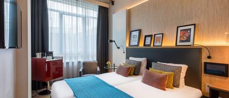 A hotel room with a large bed, a desk, a chair, and a TV.