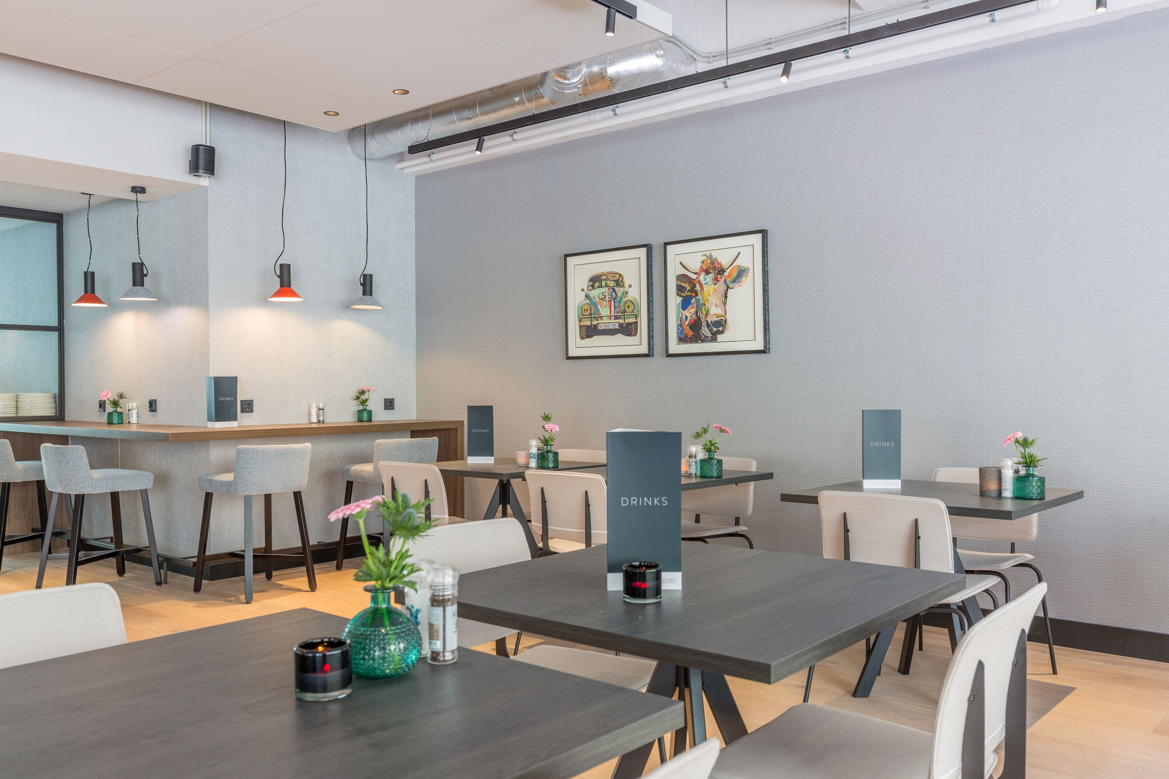 Um hall de hotel moderno com área de bar, espaços para sentar e obras de arte nas paredes.