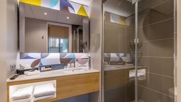 A modern bathroom with a large mirror, two sinks, a shower, and a towel rack.