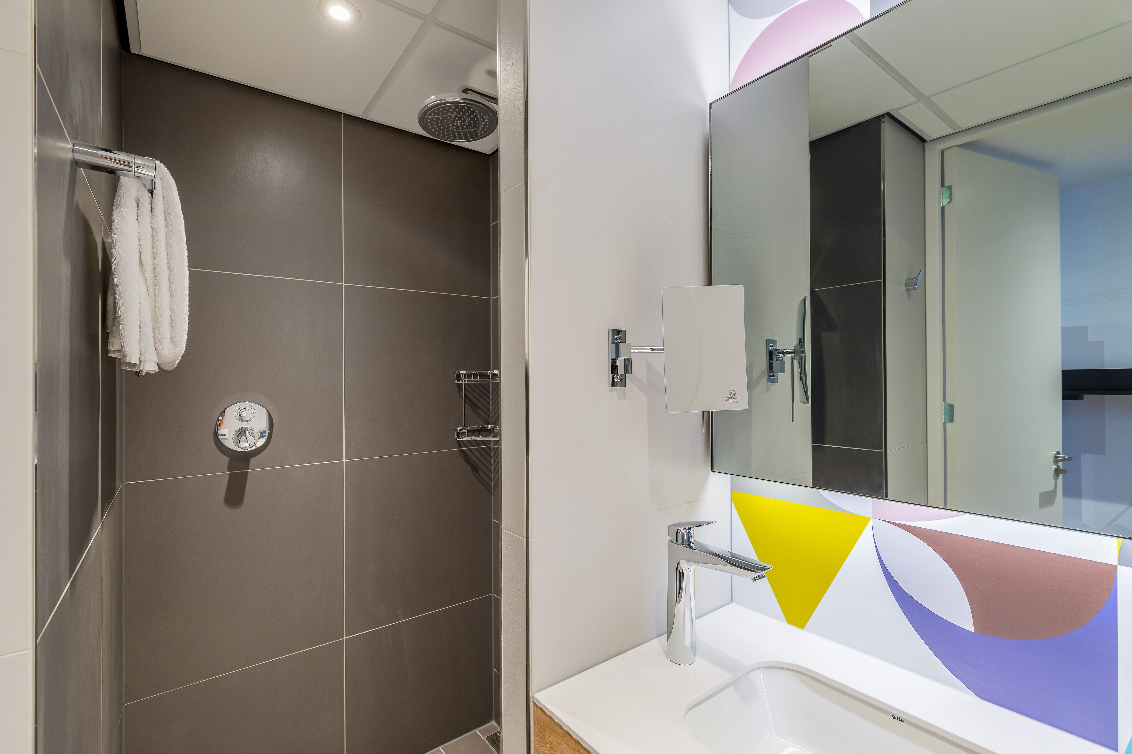 A modern bathroom with a shower, a sink, and a mirror.