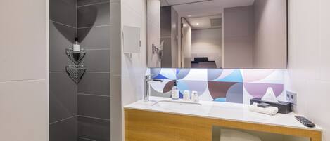 Une salle de bain moderne équipée d’une douche, d’un lavabo avec un miroir et d’un porte-serviettes.