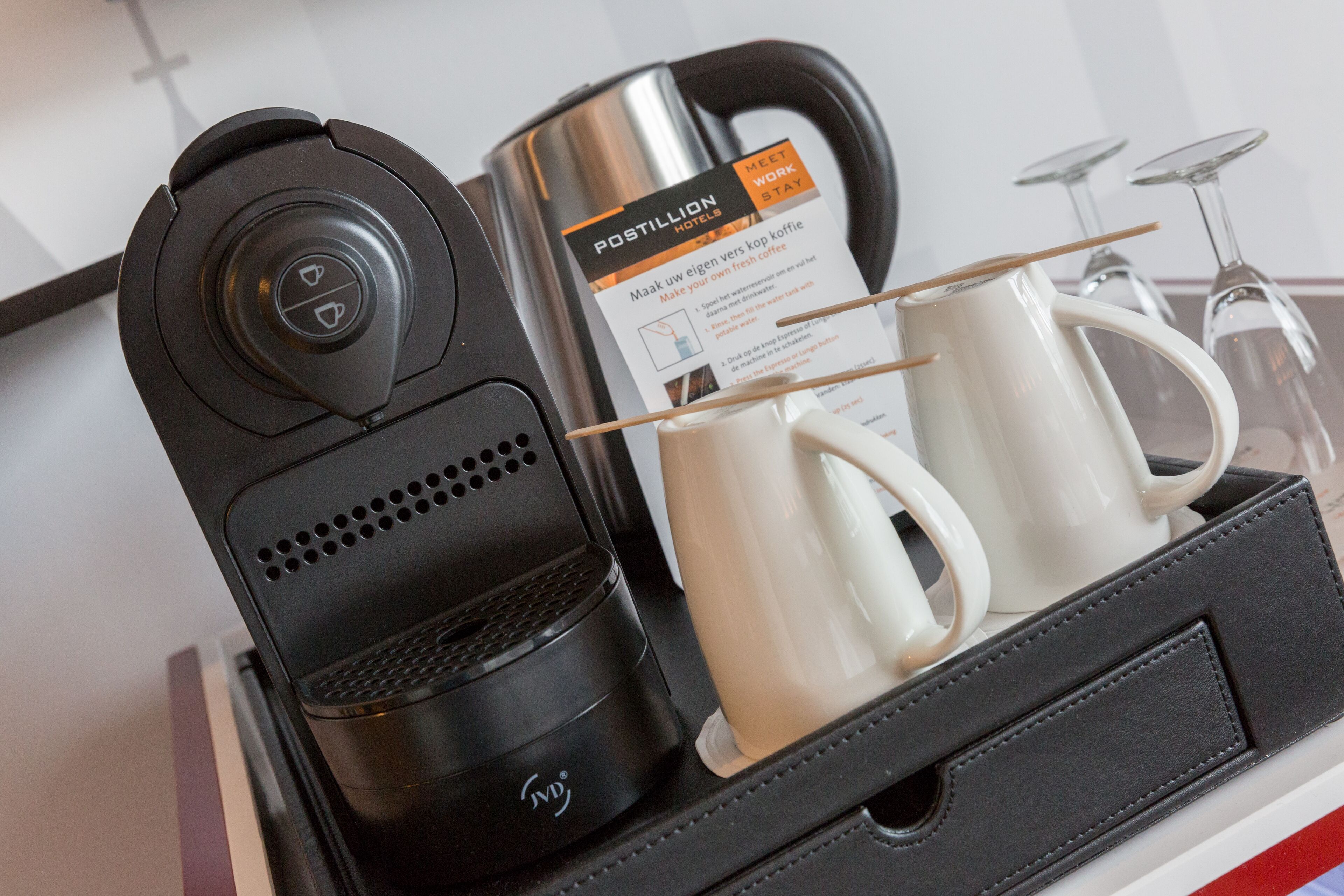 A coffee maker, a coffee pot, and two white mugs on a tray.
