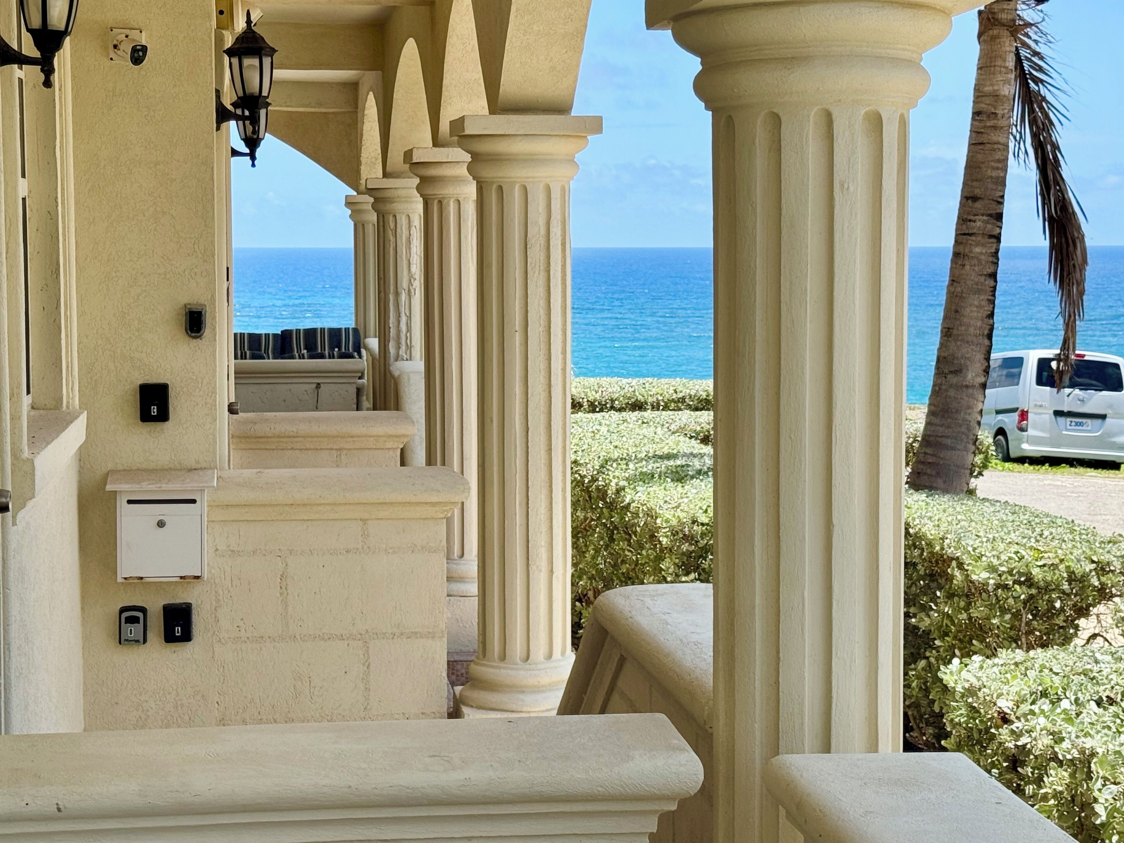 Un balcon orné de colonnes, une vue sur la mer et un fourgon garé.