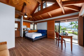A modern bedroom with a large bed, a dining area, and a view of the outdoors. - Summer Deal Kona Oceanfront Estate with Pool Water Slide Guest House (Kauilua Kona)