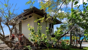 A two-story building with a staircase leading to the upper floor, surrounded by lush greenery and a view of the ocean. - Summer Deal Kona Oceanfront Estate with Pool Water Slide Guest House (Kauilua Kona)