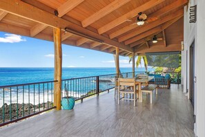 A covered outdoor area with a wooden ceiling, a view of the ocean, a wooden table and chairs, and a potted plant. - Summer Deal Kona Oceanfront Estate with Pool Water Slide Guest House (Kauilua Kona)