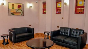 A lounge area with two black leather sofas, a round table, and a small round table. - Davana Hotel (Nairobi)