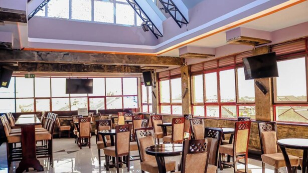 A restaurant with high ceilings, large windows, and a mix of wooden and upholstered chairs. - Davana Hotel (Nairobi)