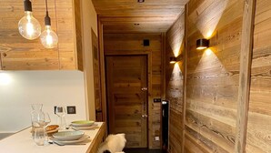 Ein modernes Interieur mit einer Holzwand und -decke, einem Essbereich mit Tisch und Stühlen sowie einem Flur, der zu einer Tür führt.