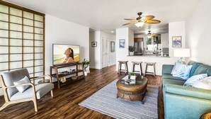 A modern living room with a sofa, armchair, coffee table, and a television.