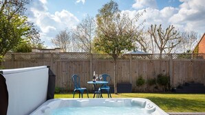 A backyard with a hot tub, two chairs, and a table with drinks. - Cotswold Barn Conversion With Private Hot Tub (Pershore)
