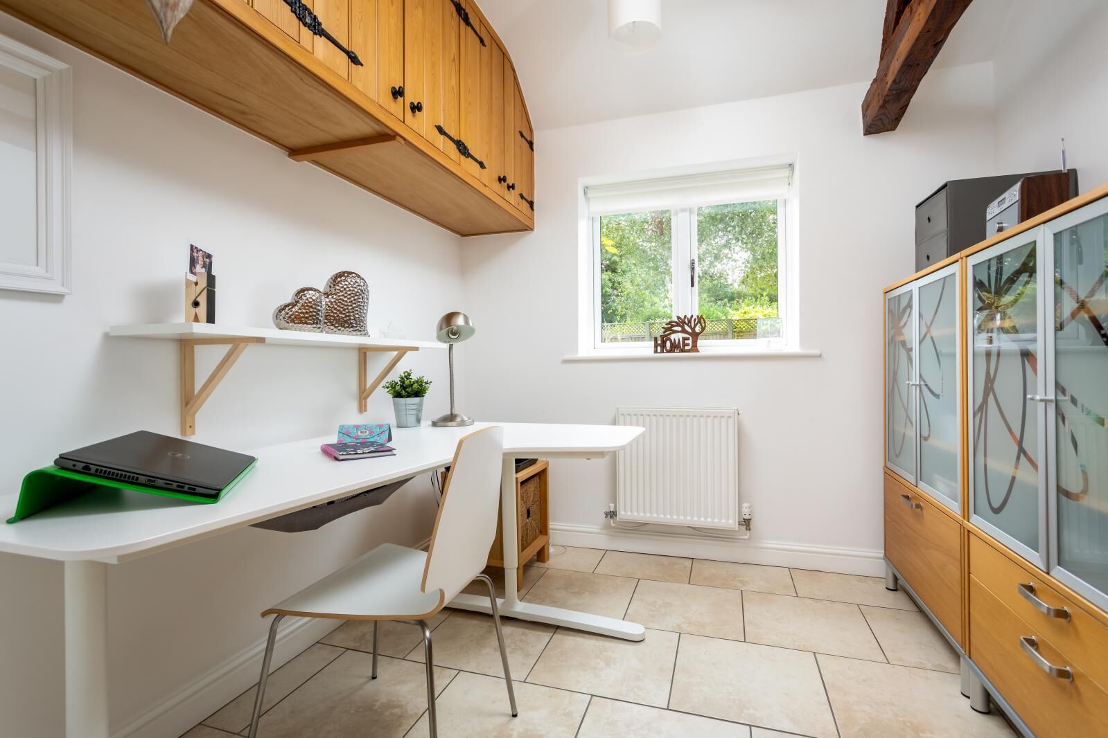 Une cuisine compacte avec un plan de travail blanc, un meuble en bois, un radiateur et une fenêtre donnant sur un espace verdoyant.