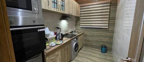 A compact kitchen with a built-in oven, microwave, and washing machine.