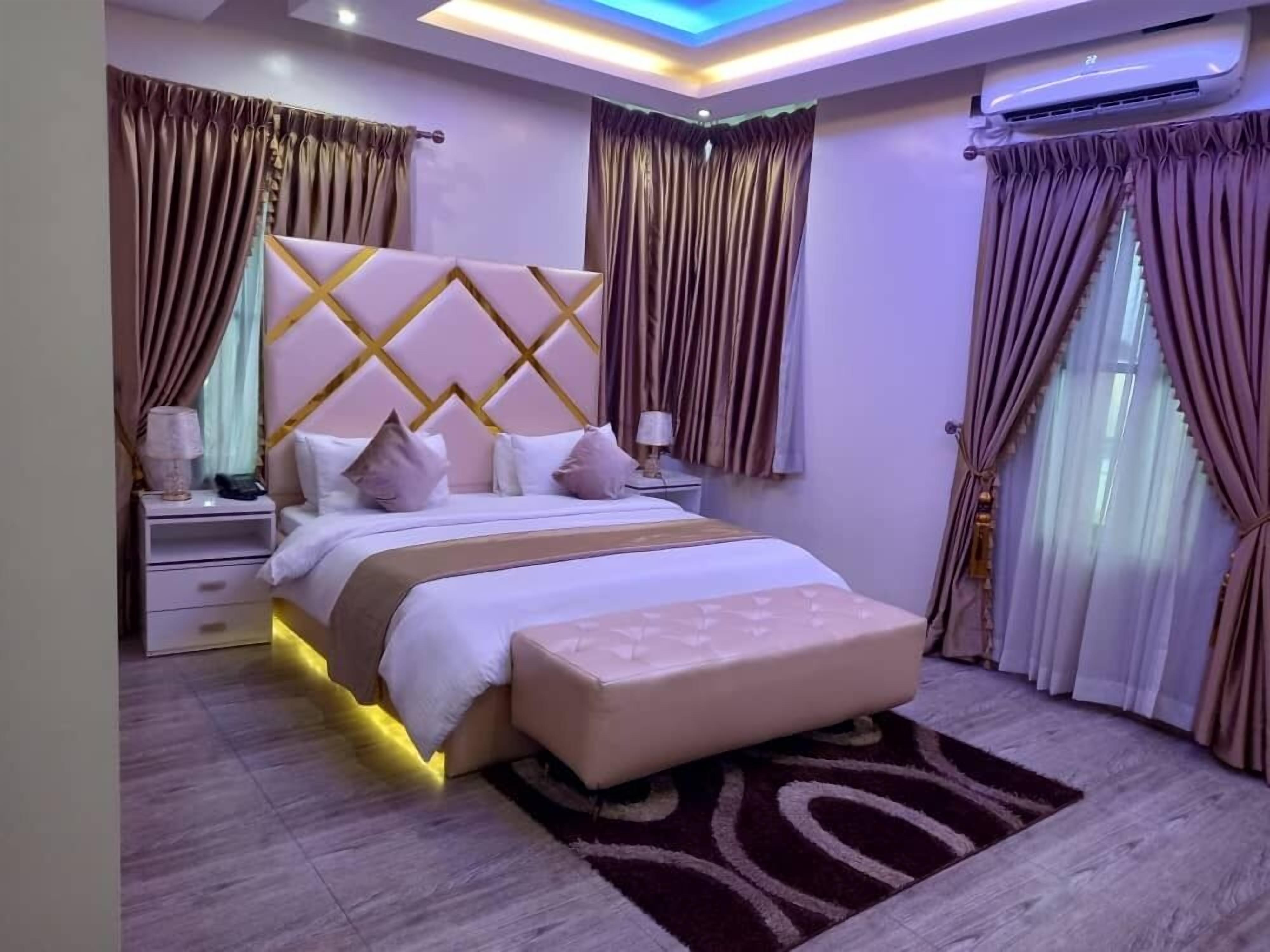 A modern bedroom with a large bed, a nightstand, a bedside table, and a wall-mounted air conditioner.