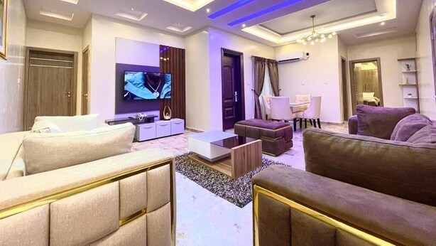 Ein modernes Wohnzimmer mit Flachbildfernseher, Sofas, einem Couchtisch und einer Deckenleuchte.