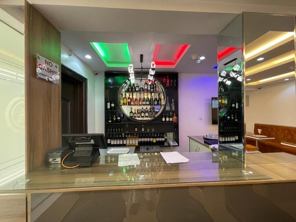 A bar area with a cash register, a counter with papers, and a wall of liquor bottles.