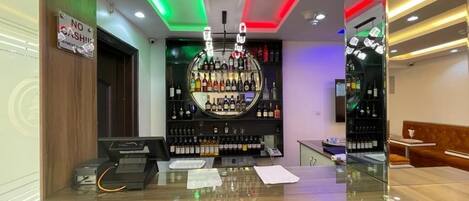 A bar area with a cash register, a counter with papers, and a wall of liquor bottles.