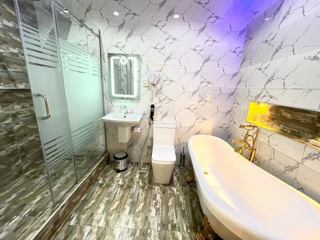 Une salle de bain moderne avec une douche à l’italienne en verre, un lavabo blanc, des toilettes et une baignoire sur pieds.