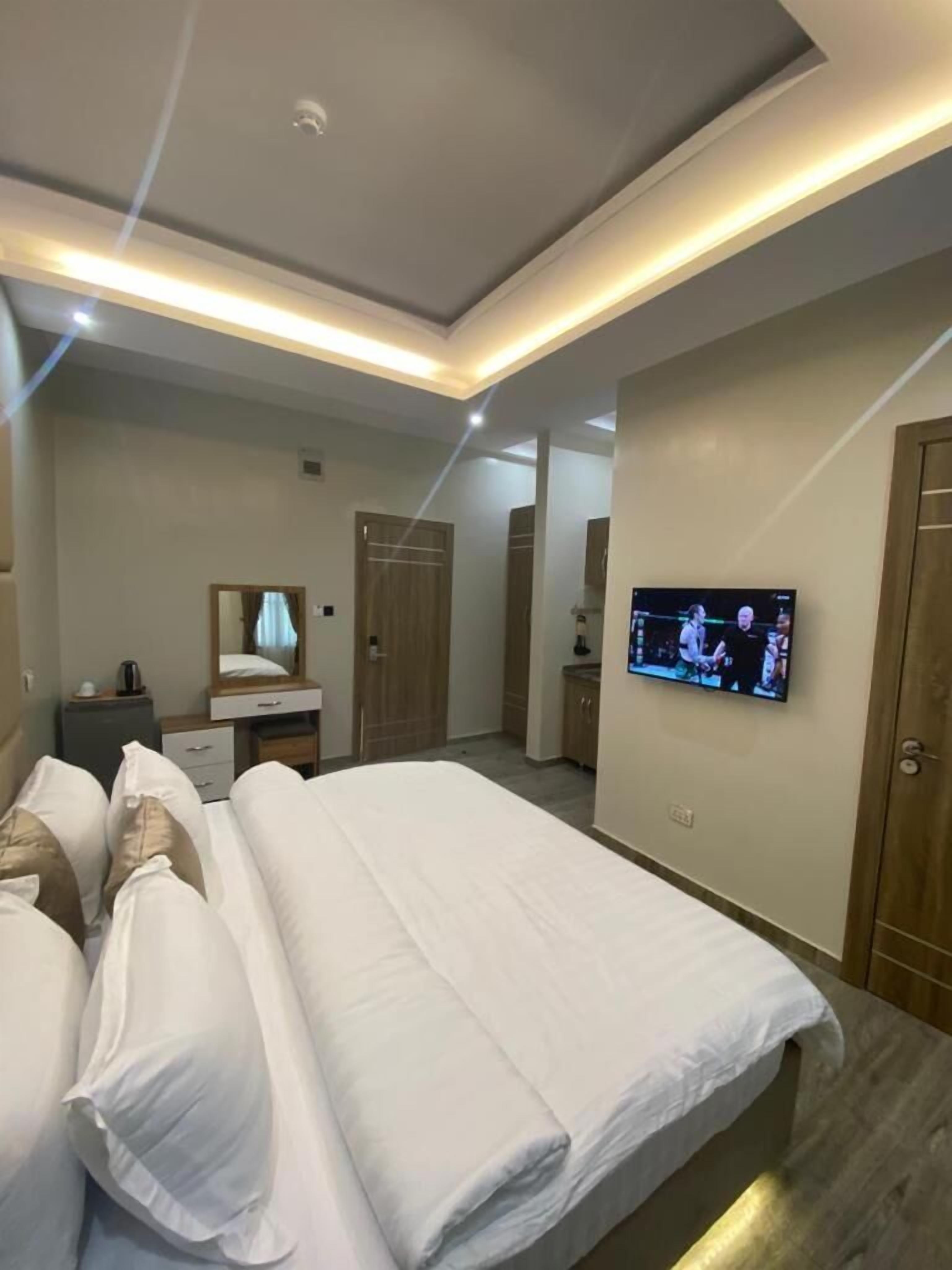 Een moderne hotelkamer met een net opgemaakt bed, een aan de muur bevestigde televisie en een klein bureau met een spiegel.