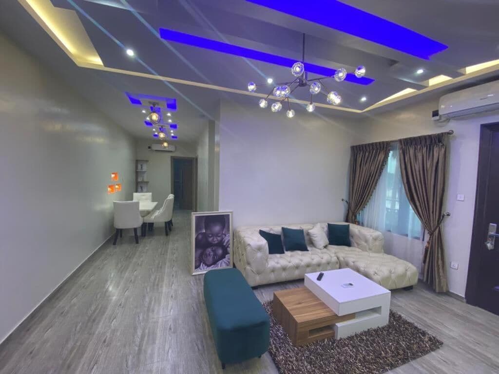 A modern living room with a sectional sofa, a coffee table, and a dining area with a table and chairs.