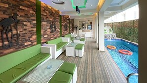 Ein Poolbereich mit Sitzgelegenheiten, einer Ziegelwand und einem Pool.