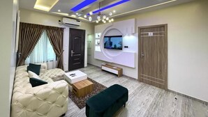 Ein modernes Wohnzimmer mit einer Couch, einem Couchtisch, einem an der Wand befestigten Fernseher und einer Holztür.