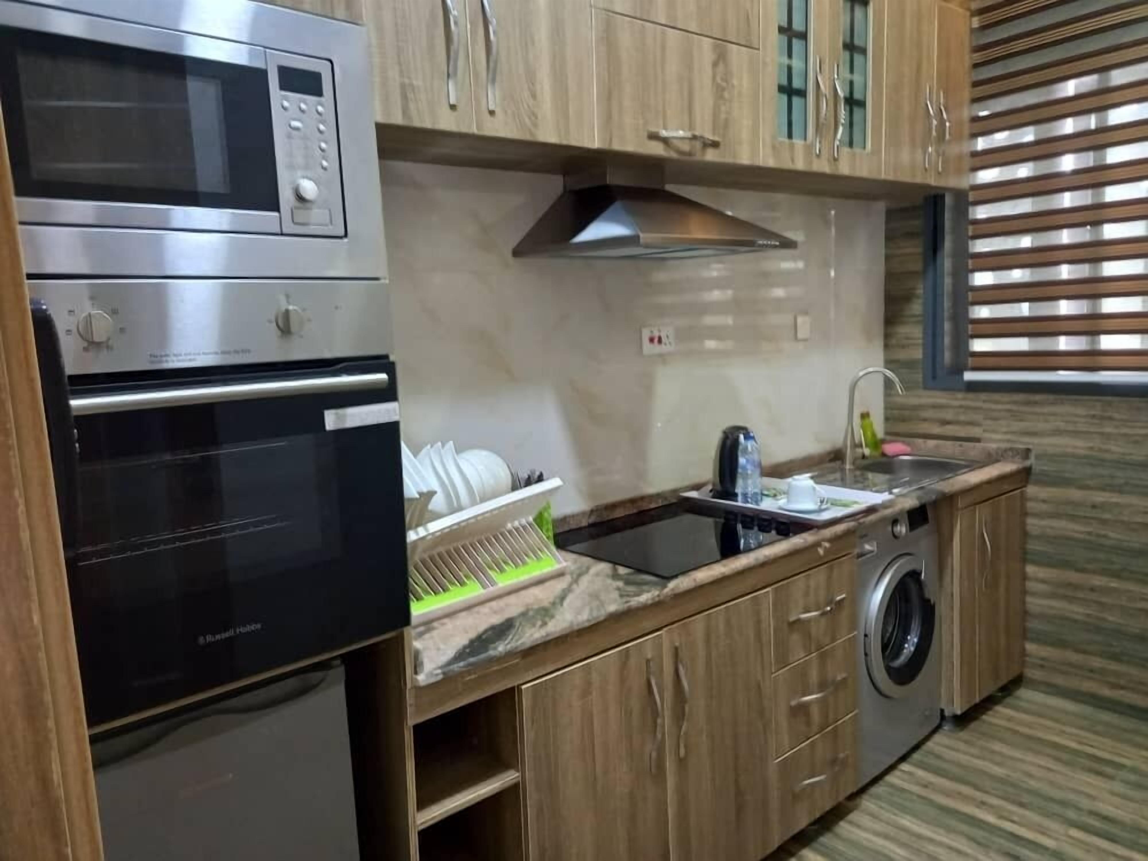 Una cucina compatta con forno a microonde, forno, lavello e lavatrice.