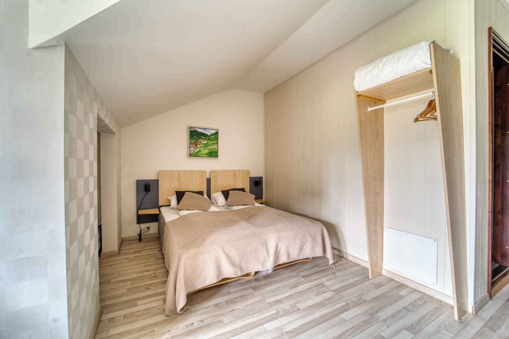 Ein Schlafzimmer mit einem Bett, einem Nachttisch, einem an der Wand montierten Fernseher und einem Holzschrank.