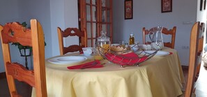 A dining area with a table set for two, featuring a potted plant and comfortable chairs.