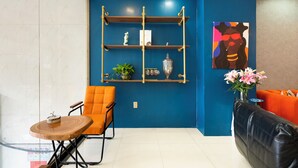Una sala de estar moderna con una pared azul de acento, un estante de madera con adornos, un sofá de cuero y una pequeña mesa redonda con un pastel.