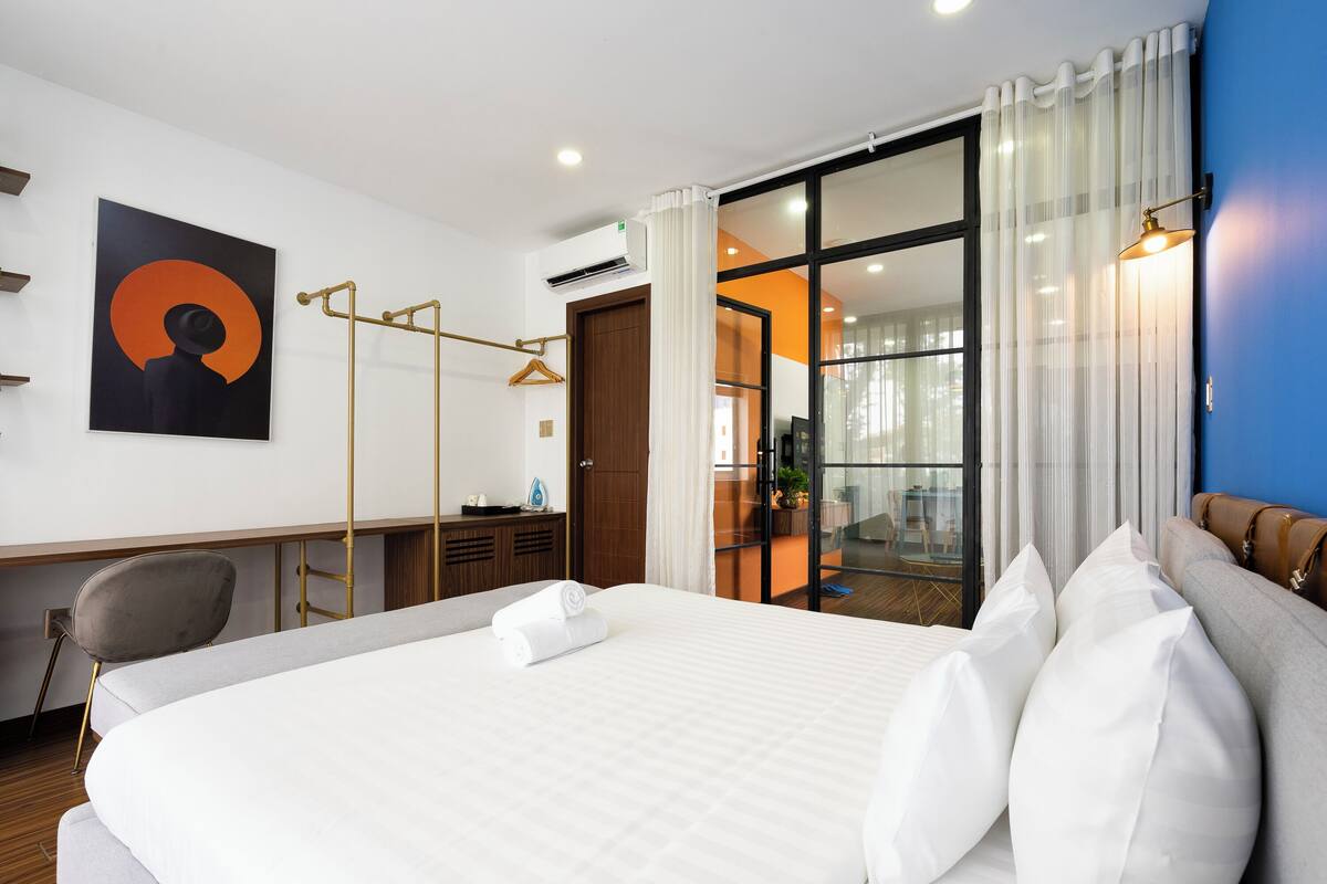 A modern hotel room with a large bed, a desk, and a chair.