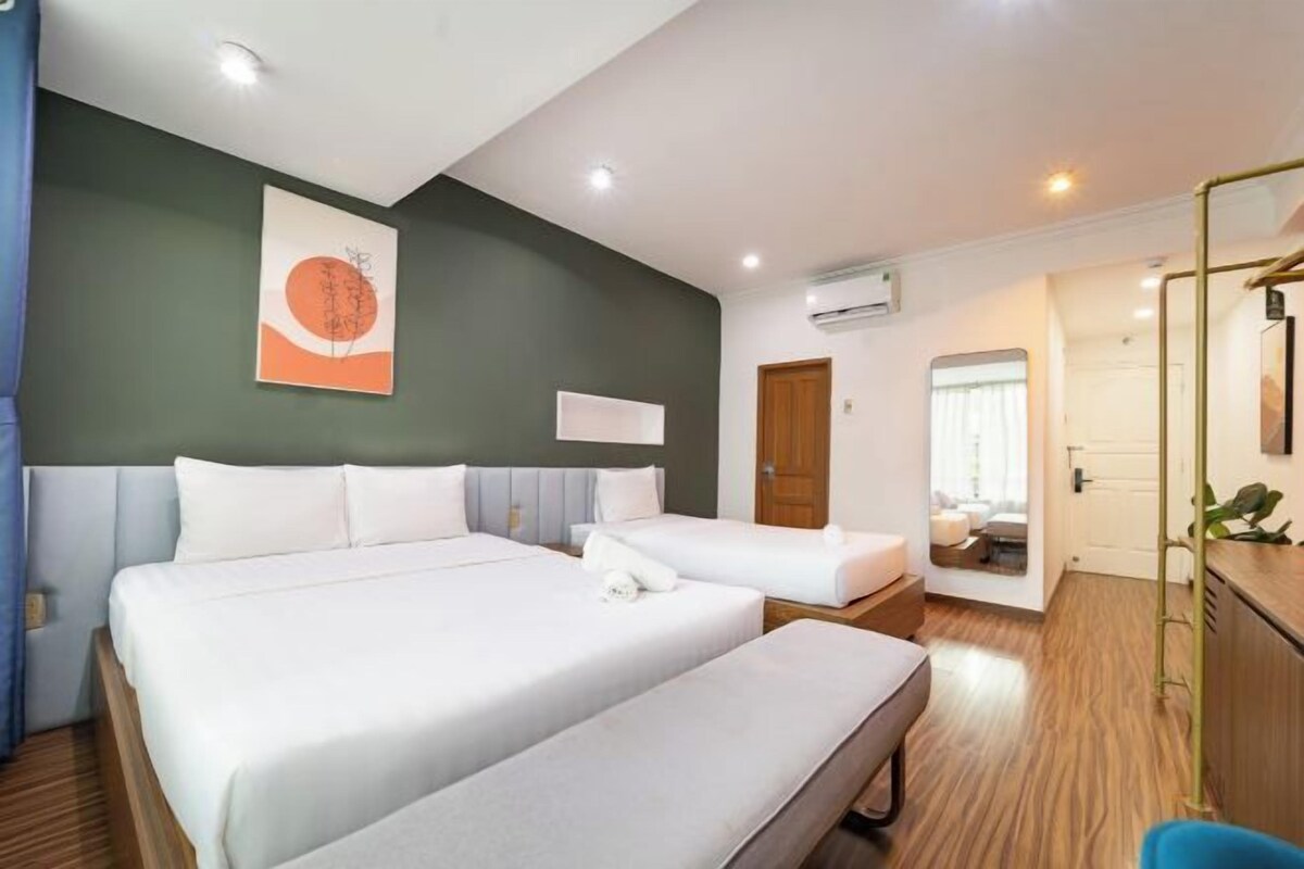 Una habitación de hotel con una cama grande, una cama más pequeña, un escritorio y un espejo.