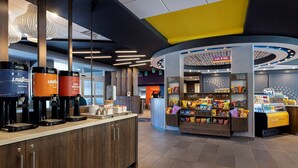 Un espace café moderne doté de plusieurs distributeurs de café et d’un coin collation proposant divers produits emballés.