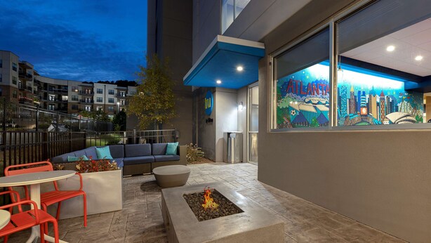 Un espace extérieur aménagé en terrasse, avec un foyer, des sièges et une vue sur le paysage urbain.