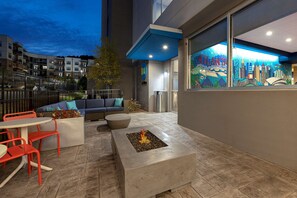 An outdoor patio area with a fire pit, seating, and a view of the cityscape.