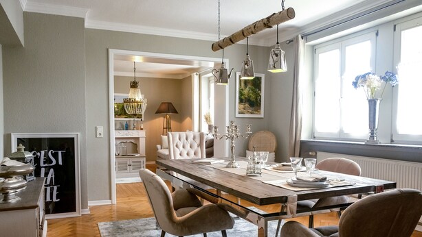 A dining area with a wooden table, cushioned chairs, and hanging pendant lights. - 80qm Ruhige, Grüne Innenstadtlage 10 Min. zur Pulsierenden Altstadt (Saarlouis)