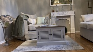 A living room with a wooden floor, a grey sofa, a coffee table, a chandelier, and a fireplace. - 80qm Ruhige, Grüne Innenstadtlage 10 Min. zur Pulsierenden Altstadt (Saarlouis)