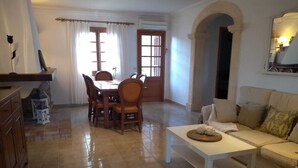 Zona pranzo con tavolo e sedie, un divano e un pavimento piastrellato.