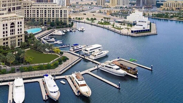 A marina with several yachts docked, surrounded by modern buildings and a clear sky. - Kingsgate Canal Hotel (Dubai)