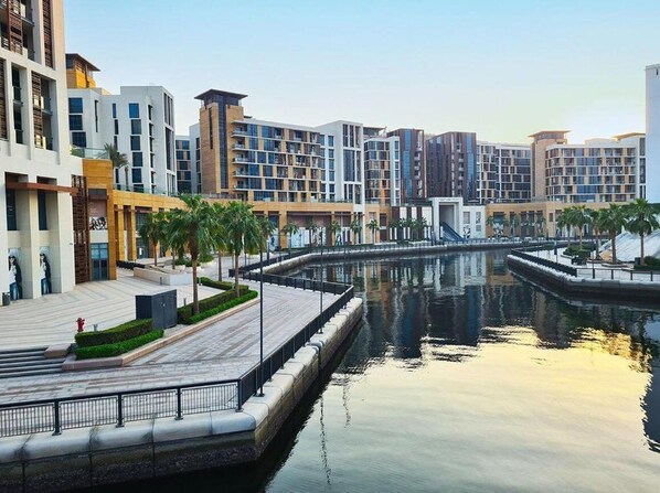 A modern hotel complex with multiple buildings, a central water feature, and a well-maintained outdoor area with palm trees.