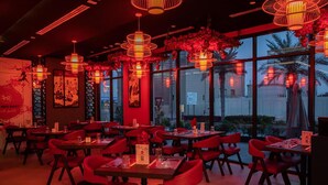 A restaurant with red lighting, multiple tables, and chairs. - Kingsgate Canal Hotel (Dubai)
