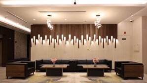 A modern lobby with a black leather sofa, two side tables, and a decorative wall panel. - Kingsgate Canal Hotel (Dubai)
