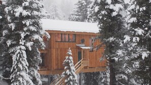 A wooden cabin with a balcony and stairs, surrounded by snow-covered trees. - Chalet Royal with in-house wellness and large living room, large new balcony #23 (Turrach)