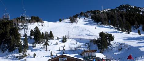 A ski resort with a wooden lodge, ski lifts, and a snowy mountain backdrop.