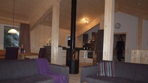 A cozy living room with two sofas, a wooden coffee table with magazines, and a kitchen in the background. - Chalet Royal with in-house wellness and large living room, large new balcony #23 (Turrach)